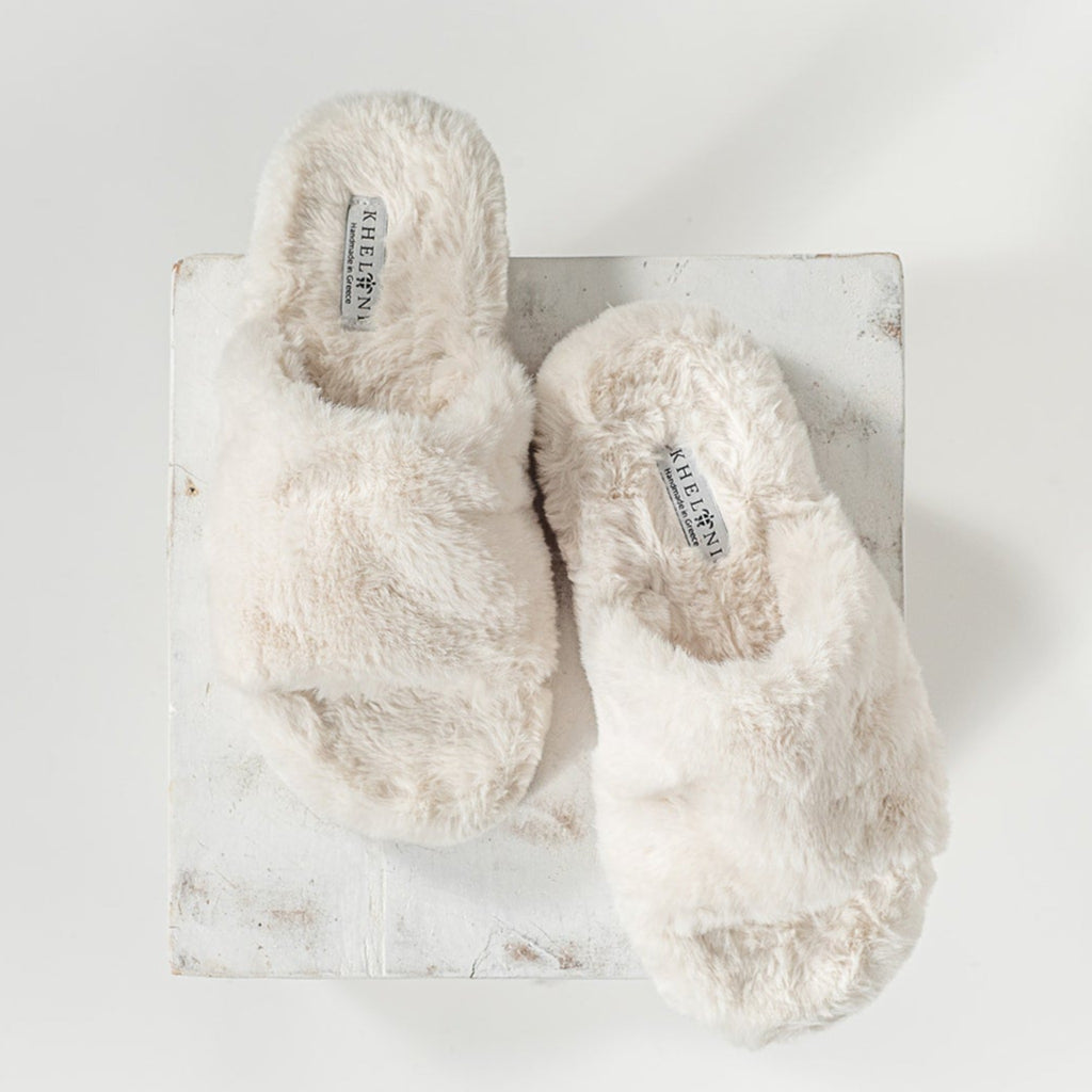 Looking down on cream colored soft faux slippers in a contemporary setting.