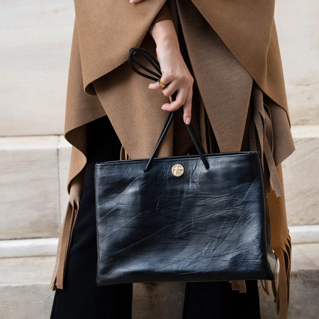 Woman holding a Gabi Handbag | Made with creased cowhide leather and adorned with our solid brass Kheloni coin.
