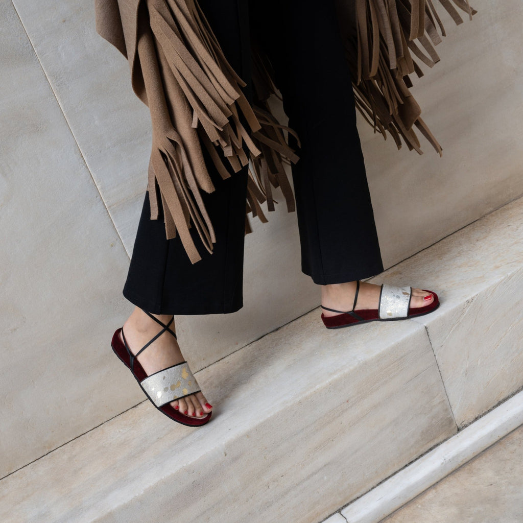 woman wearing burgundy velvet and gold acid wash leather slides for a festive look.