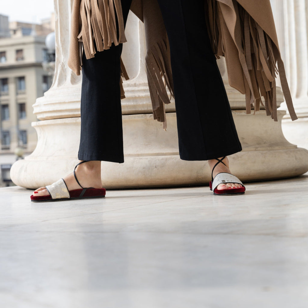 woman wearing burgundy velvet and gold acid wash leather slides for a festive look.