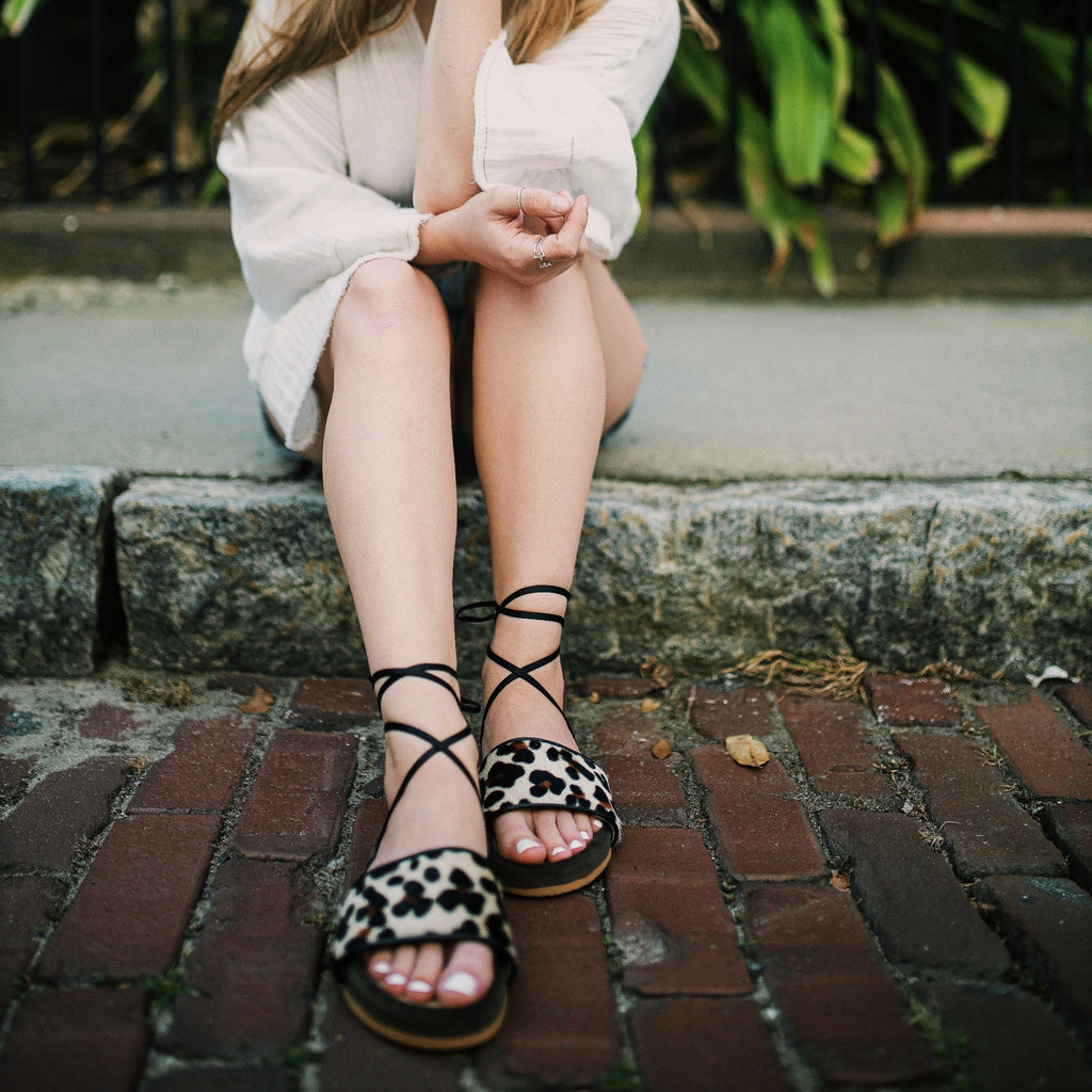 Woman wearing Rita | Handmade Greek slides with Jaguar print that are wrapped in rich dark brown velvet.